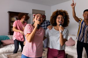 happy diverse friends dancing and karaoke singing with microphone at home. domestic life, friendship, music and lifestyle, unaltered.